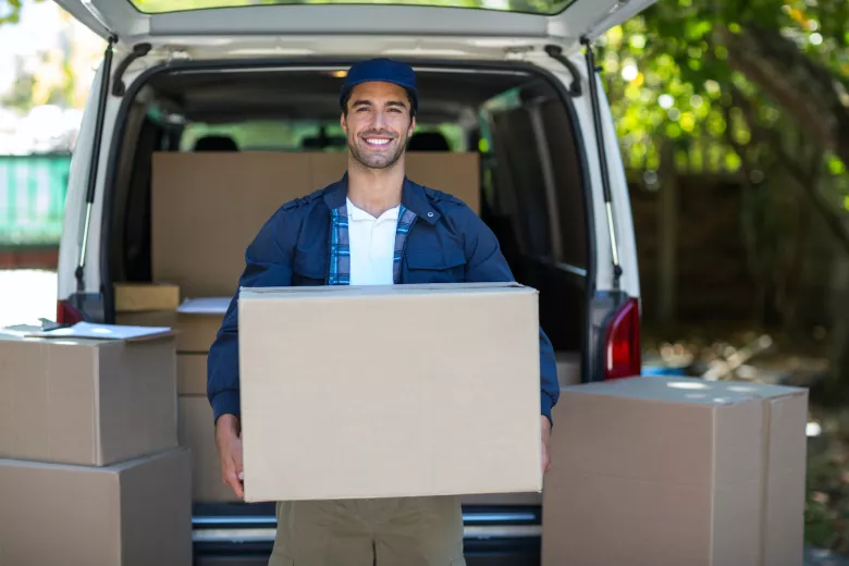 Man carrying storage box in front of van