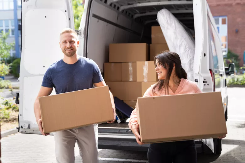 Smiling couple with storage boxes in front of van